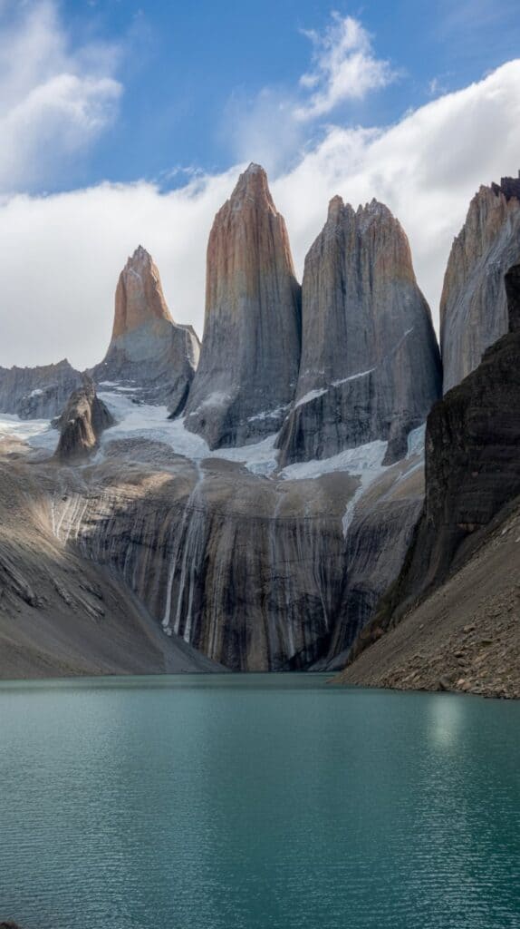 Standing at the edge of a mirror-like lake as the Paine Massif glows pink in the sunrise.